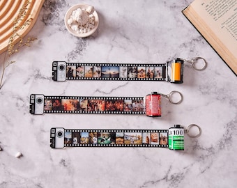 May include: Three black and white photo strips with colourful film canisters attached. The strips feature images of people and landscapes. The canisters are labelled "24", "100", and "FUJICOLOR".
