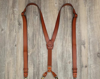 May include: Brown leather suspenders with gold-tone clips and a personalized leather patch with the initials "SK".