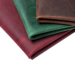 Puede incluir: Tres piezas de cuero en diferentes colores: rojo, verde y marr&oacute;n. El cuero est&aacute; doblado y apilado uno encima del otro.