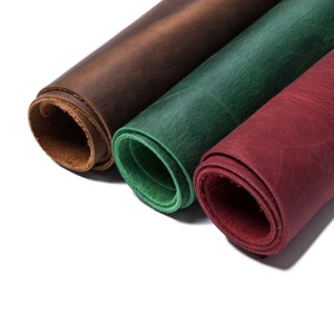 Puede incluir: Tres rollos de cuero en diferentes colores: marr&oacute;n, verde y rojo. El cuero est&aacute; enrollado y los extremos son visibles.