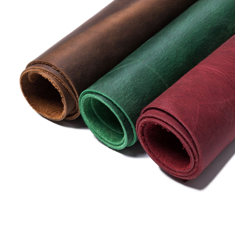 Puede incluir: Tres rollos de cuero en diferentes colores: marr&oacute;n, verde y rojo. El cuero est&aacute; enrollado y los extremos son visibles.