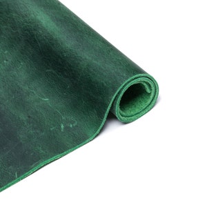 Puede incluir: Un rollo de cuero verde oscuro con una superficie texturizada.