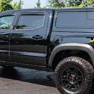 K&ouml;nnte beinhalten: Schwarzer Pickup-Truck mit schwarzer Pritschenabdeckung und einem "TRD"-Aufkleber an der Seite. Der Truck hat schwarze R&auml;der und einen schwarzen K&uuml;hlergrill.