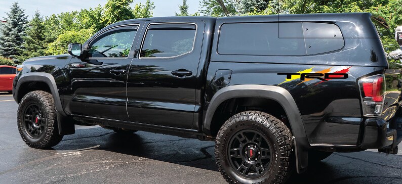 K&ouml;nnte beinhalten: Schwarzer Pickup-Truck mit schwarzer Pritschenabdeckung und einem "TRD"-Aufkleber an der Seite. Der Truck hat schwarze R&auml;der und einen schwarzen K&uuml;hlergrill.