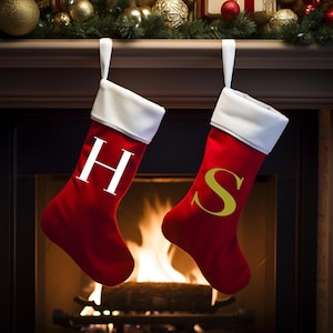 Może przedstawiać: Dwie czerwone świąteczne skarpety z białymi mankietami wiszące na kominku. Skarpety po lewej stronie mają białe "H", a skarpety po prawej stronie mają złote "S".