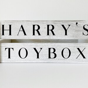 K&ouml;nnte beinhalten: Wei&szlig;e Holzspielzeugkiste mit schwarzer Beschriftung "HARRY'S TOYBOX".