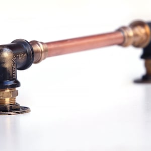 May include: A black and copper pipe handle with a brass fitting and a black base. The pipe is labelled "MADE IN ITALY".