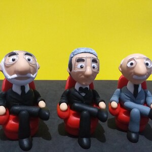 May include: Three miniature figurines of men sitting in red armchairs. The men are wearing suits and have white hair. The figurines are made of clay and are hand-painted.