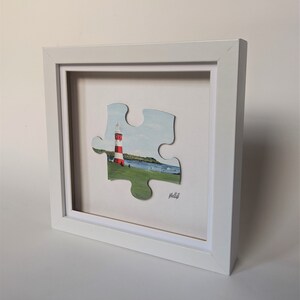 Pu&ograve; includere: Un pezzo di puzzle bianco incorniciato con un faro e un campo verde sullo sfondo. Il pezzo di puzzle &egrave; rialzato rispetto allo sfondo ed &egrave; circondato da una cornice bianca. Il testo "Molly" &egrave; scritto nell'angolo in basso a destra dell'immagine.