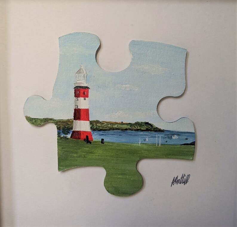 Pu&ograve; includere: Un dipinto di un faro rosso e bianco su una collina verde erbosa con uno specchio d'acqua blu sullo sfondo. Il dipinto &egrave; su un pezzo di puzzle.