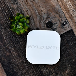 May include: White square-shaped device with the text "WYLD LYTE" printed on it.