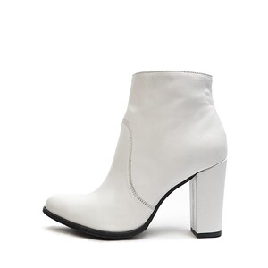 May include: White leather ankle boots with a block heel. The boots have a pointed toe and a zipper on the back.