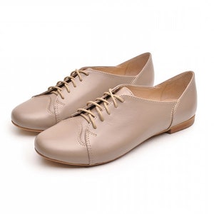 May include: A pair of beige leather lace-up shoes with a low heel.
