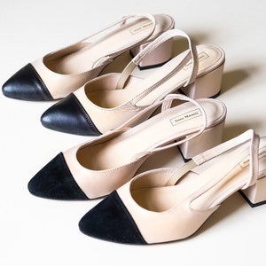 May include: Three pairs of beige heeled slingback shoes with black toe caps. The shoes have a block heel and are made by Anna Maratti.