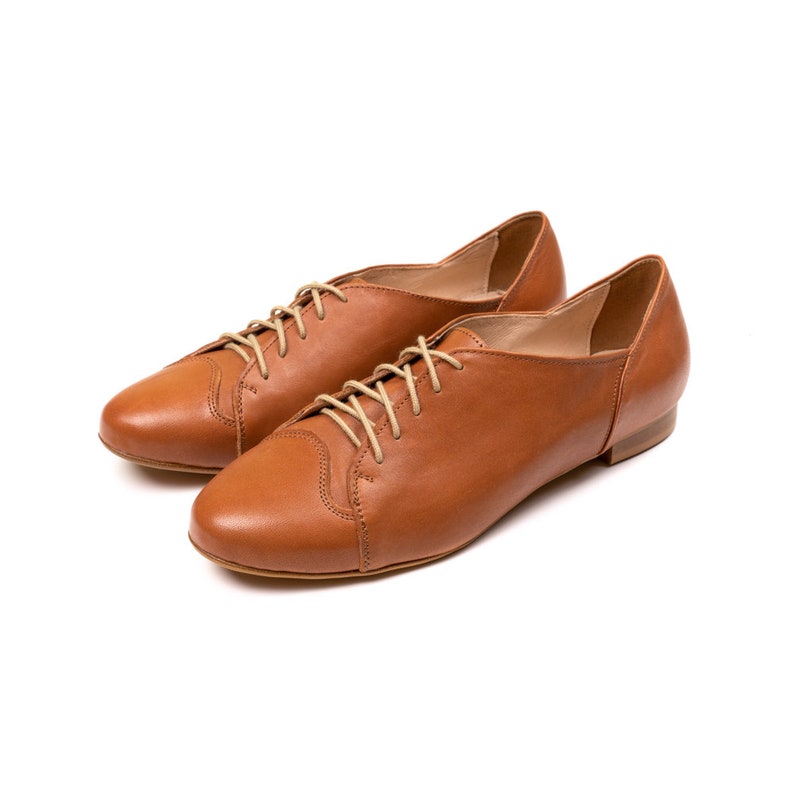 May include: A pair of brown leather lace-up shoes with a low heel.