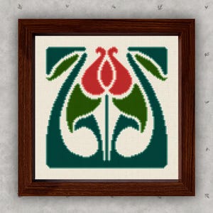 May include: A framed cross-stitch art piece featuring a stylized floral design. The artwork showcases a central red flower with green leaves and stems, set against a cream background and a dark teal border. The frame is a dark brown color.