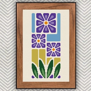 May include: A framed cross-stitch art piece featuring a floral design. The artwork showcases purple flowers with orange centers, blue and yellow geometric shapes, and green leaves. The frame is made of wood.