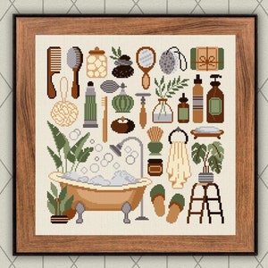 Könnte beinhalten: Ein gerahmtes Kreuzstich-Design mit einer Badezimmer-Szene mit einer Badewanne, Handtüchern, Pflanzen und verschiedenen Toilettenartikeln. Das Design ist in einer gedeckten Farbpalette aus Grün, Braun und Creme gehalten.