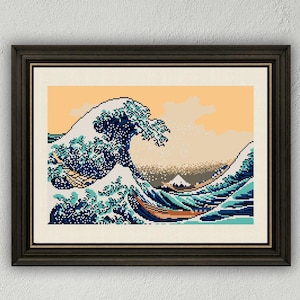 May include: Framed pixel art print of Hokusai's "The Great Wave off Kanagawa." The artwork features a large, stylized wave in shades of blue and white, with a mountain in the background. The sky is a warm orange, and the print is in a dark wooden frame.