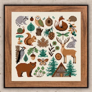 Könnte beinhalten: Ein gerahmtes Kreuzstichbild mit einem Raster aus Waldmotiven, darunter ein Waschbär, eine Eule, ein Fuchs, ein Igel, ein Eichhörnchen, ein Hirsch, ein Hase, ein Bär, eine Schnecke, ein Frosch, ein Schmetterling, ein Marienkäfer und eine kleine Hütte.
