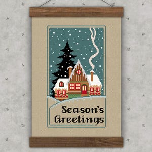Cross-stitch pattern featuring a vintage Christmas scene of a house with a chimney on a starry night and the text "Season's Greetings."