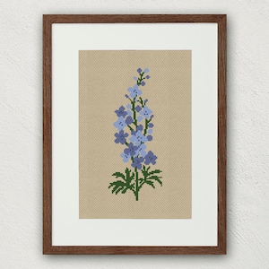 Peut inclure: Une broderie au point de croix encadrée d'une fleur bleue et verte avec un cadre brun.