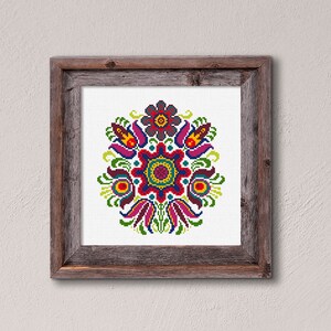 Puede incluir: Un dise&ntilde;o de punto de cruz enmarcado que presenta un patr&oacute;n floral colorido con flores rojas, amarillas, verdes, azules y moradas. El dise&ntilde;o es sim&eacute;trico y tiene un estilo de arte popular tradicional.
