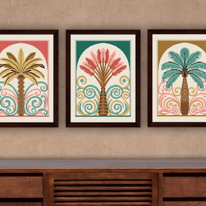 Pu&ograve; includere: Tre stampe artistiche incorniciate con palme stilizzate. Ogni stampa ha una combinazione di colori diversa: oro e rosa, rosa e verde e verde acqua e oro. Le palme sono ambientate su uno sfondo color crema all'interno di una cornice ad arco, con volute decorative.