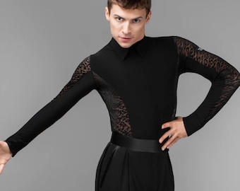 May include: A man wearing a black long-sleeved shirt with a lace pattern and black pants. He is standing with his left arm extended and his right hand on his hip.