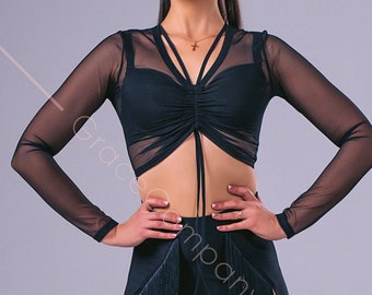 May include: A woman wearing a black mesh top with a gathered front and a black skirt with a fringe trim and side slits. She is wearing brown dance shoes.