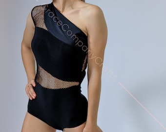 May include: A woman wearing a black one-piece leotard with a mesh panel and a single strap. The leotard has a geometric design and is form-fitting.