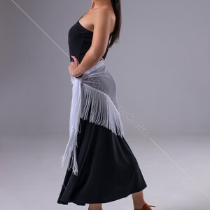 May include: A woman wearing a black one-shoulder dress with a white fringed shawl and brown dance shoes.