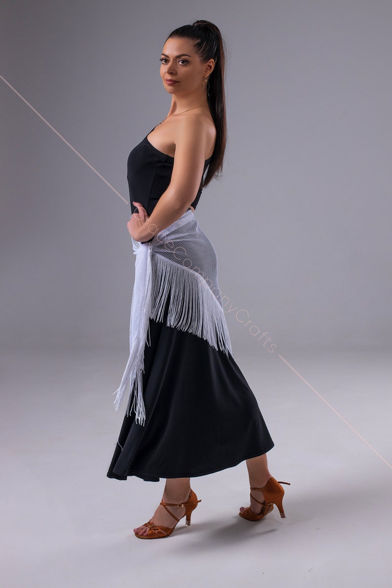 May include: A woman wearing a black one-shoulder dress with a white fringed shawl and brown dance shoes.