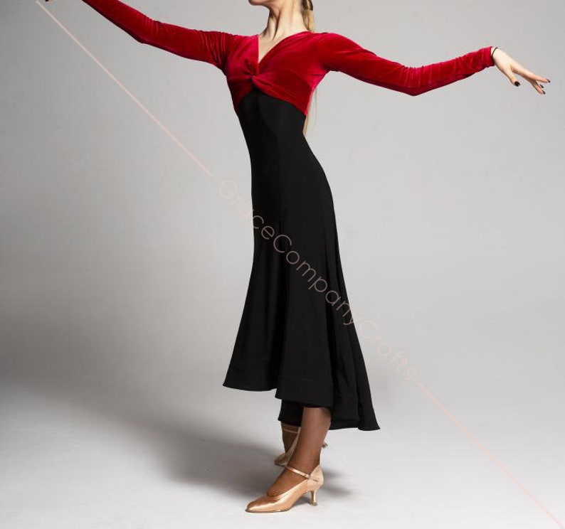 May include: A woman wearing a red velvet long-sleeved top with a black skirt. The skirt has a high waist and a flowing, asymmetrical hemline. The woman is wearing nude heels.