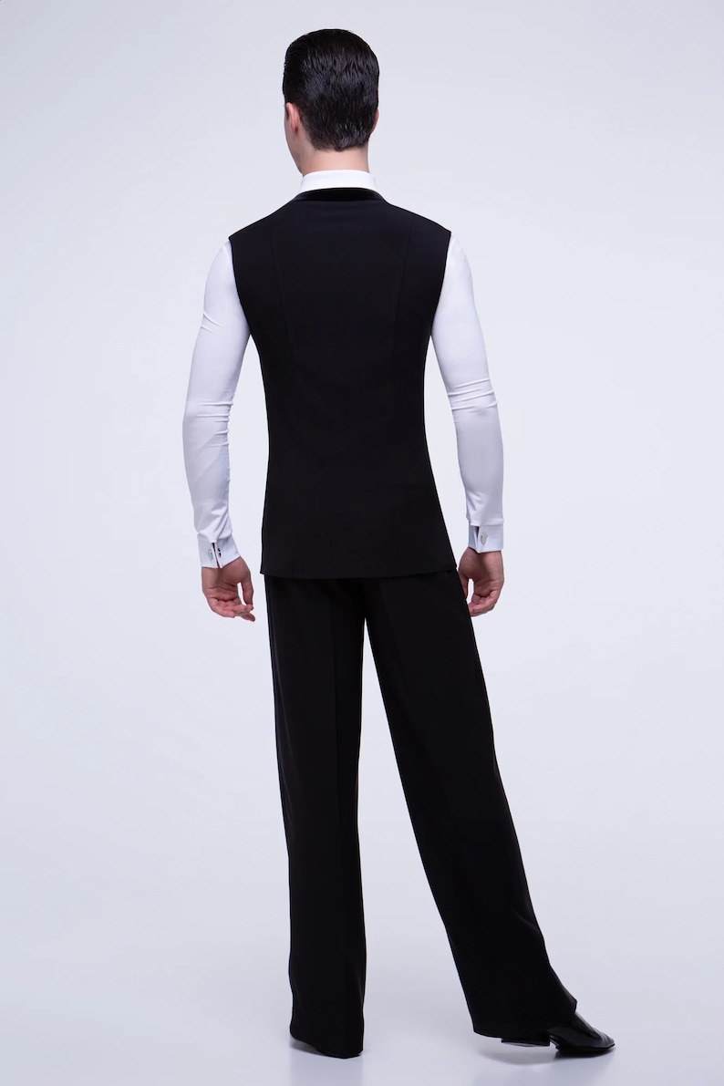 May include: A black sleeveless vest with a white long-sleeved shirt underneath. The person is wearing black pants and black shoes.