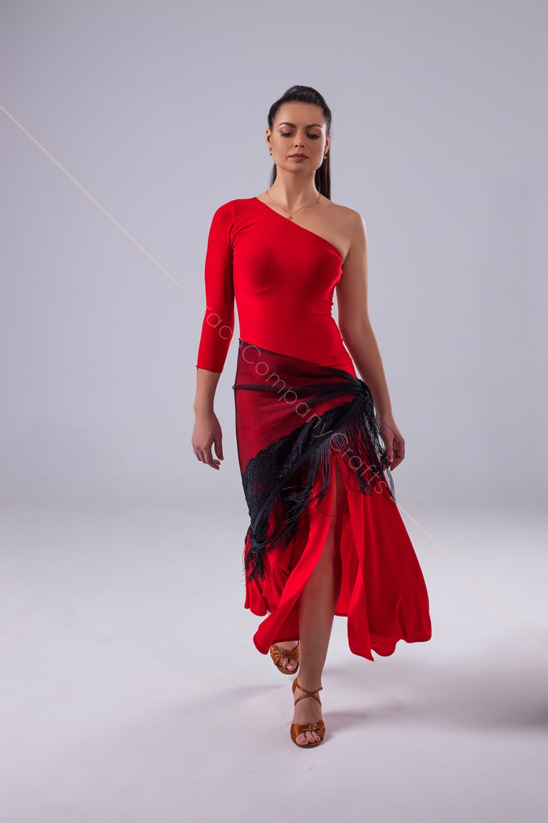 May include: A woman wearing a red one-shoulder dress with a black lace shawl and brown dance shoes.