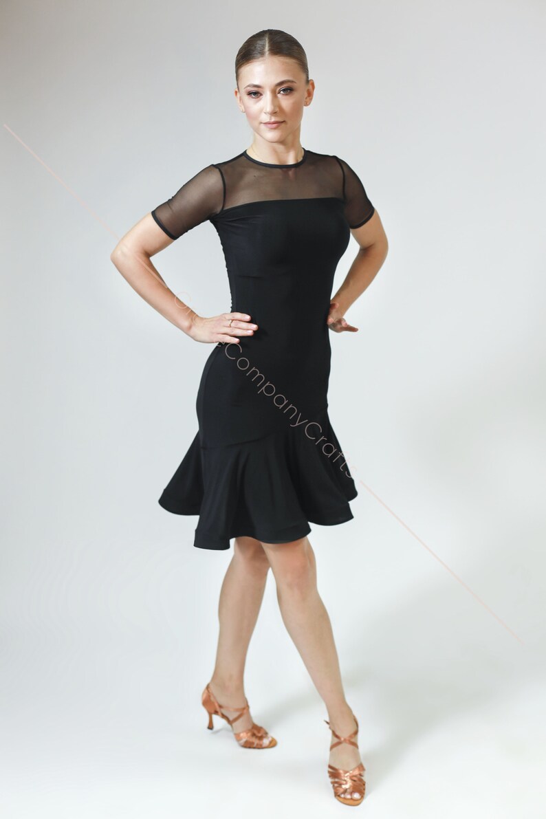 May include: A black dance dress with a mesh top and a ruffled skirt. The dress is fitted and has short sleeves.