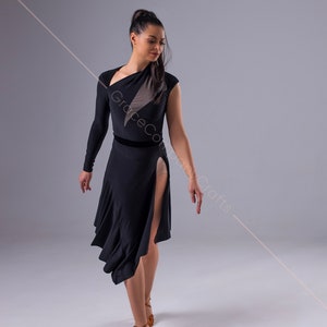 May include: A woman wearing a black dance dress with a sheer panel and a velvet waistband. She is wearing brown dance shoes and has her hair pulled back in a ponytail.