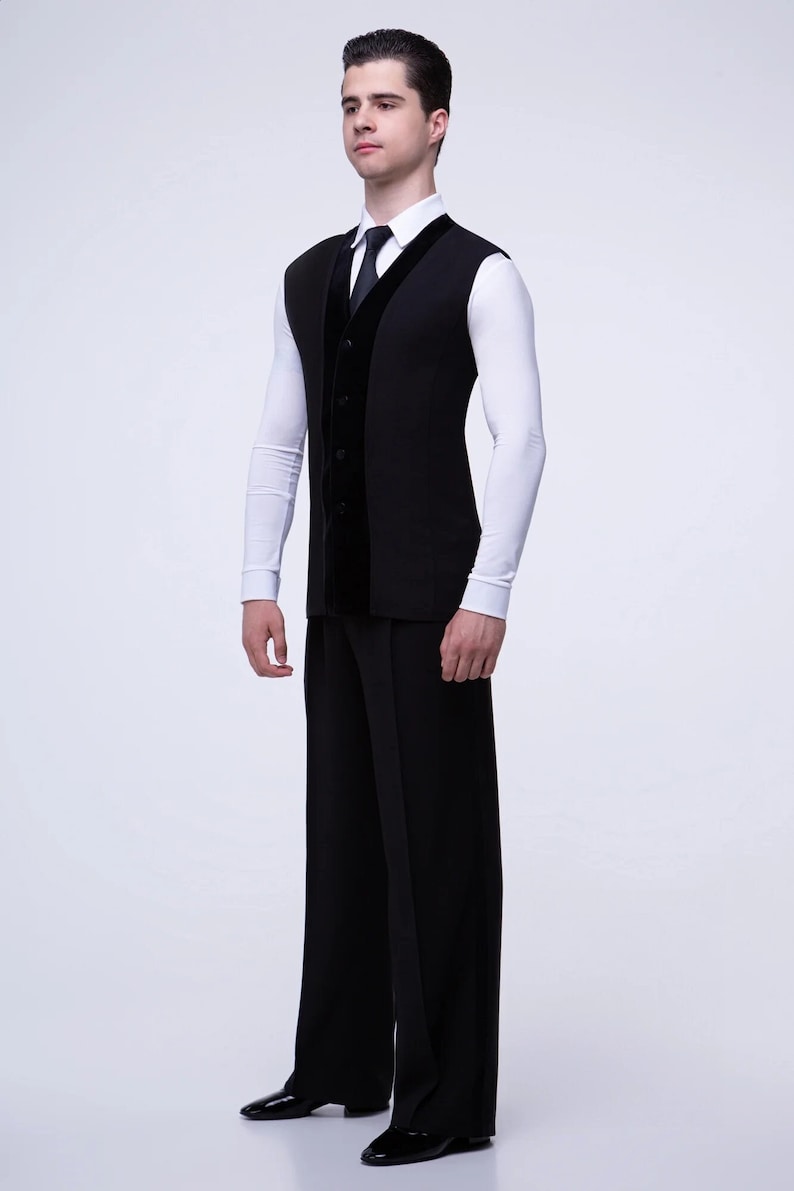 May include: A black sleeveless vest with a velvet trim and a white long-sleeved shirt with a black tie. The vest has a button closure and the shirt has a collar.