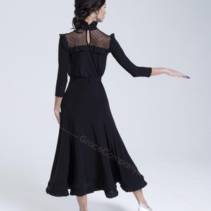 May include: A black dance skirt with a ruffled hem and a black long-sleeved top with a sheer lace yoke. The top has a high neck and a keyhole opening at the back.