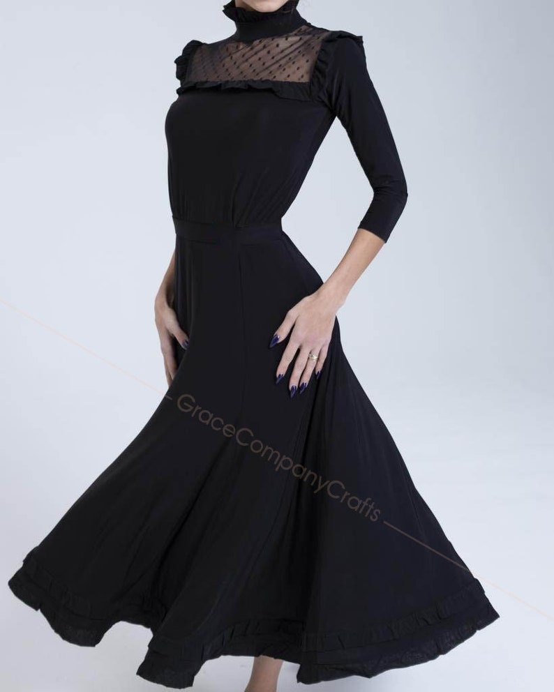 May include: A black dance dress with a high neck and a sheer polka dot mesh panel. The dress has a fitted bodice and a flowing skirt with ruffles.