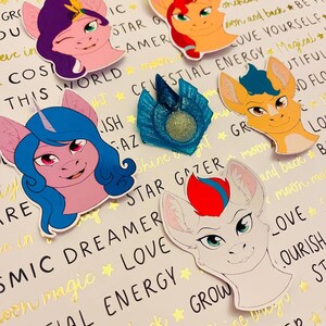 May include: Five colorful cartoon pony head stickers with different colored manes and eyes. The stickers have text around them that says "Celestial Energy", "Star Gazer", "Cosmic Dreamer", "Love", and "Grow".