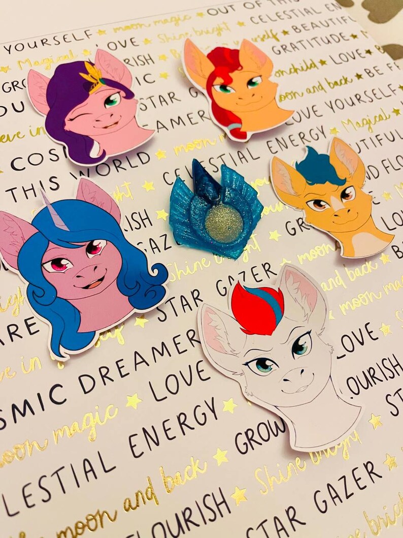 May include: Five colorful cartoon pony head stickers with different colored manes and eyes. The stickers have text around them that says "Celestial Energy", "Star Gazer", "Cosmic Dreamer", "Love", and "Grow".