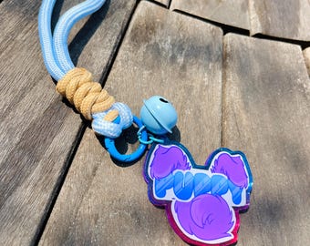 May include: A light blue and tan dog leash with a matching charm. The charm is shaped like a dog with the word "PUPPY" in blue bubble letters. A small blue bell is attached to the charm.