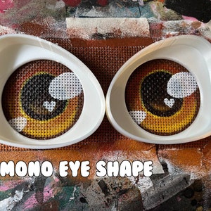 May include: Two white plastic eye shape templates for crafting. The templates are shaped like an almond with a rounded edge. The text "Kemon Eye Shape" is printed below the templates.