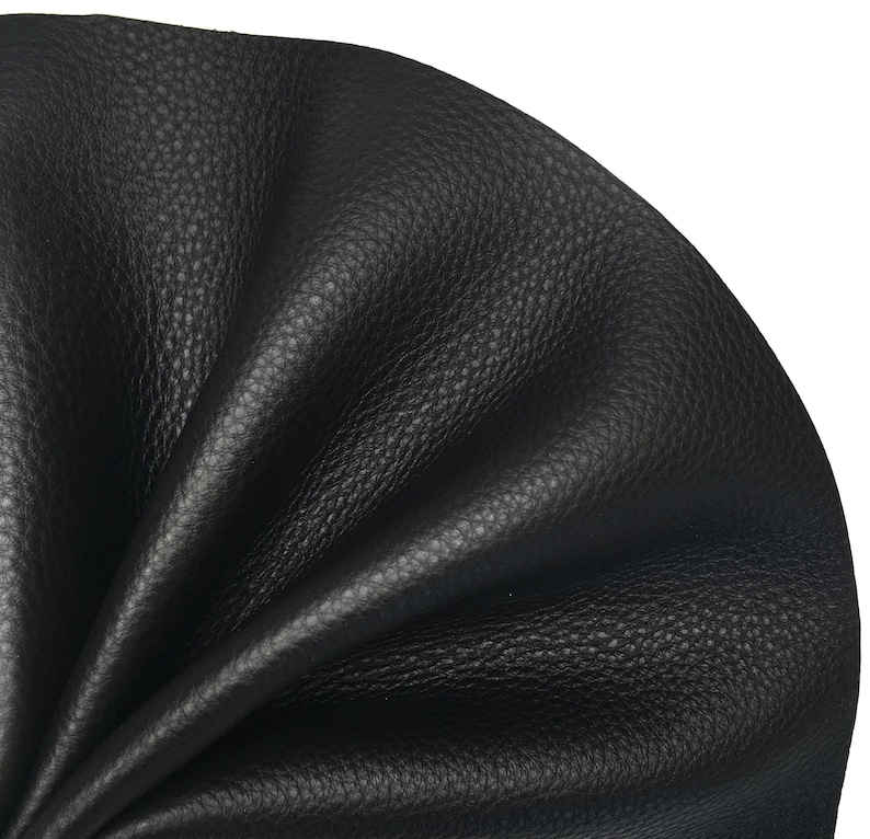 May include: Close-up of black leather with a textured surface. The leather is folded and wrinkled, showing its flexibility.