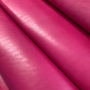 May include: Close-up of a smooth, pink leather fabric. The leather has a subtle sheen and a slightly textured surface.