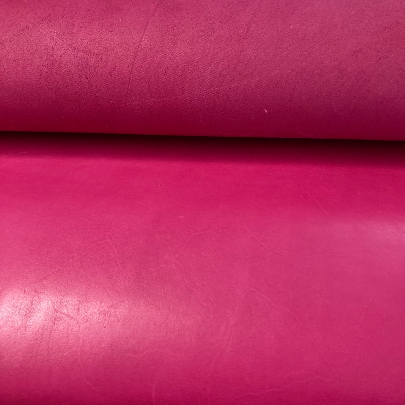 May include: Close-up of a smooth, deep pink leather material. The leather has a subtle sheen and a slightly textured surface.