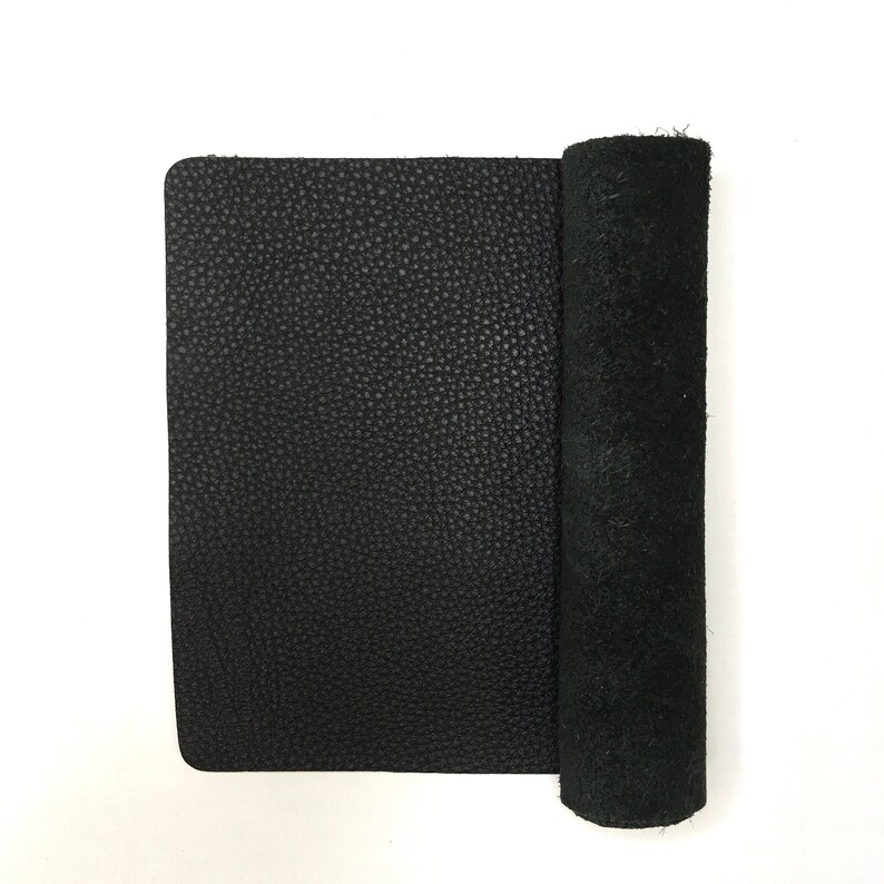 May include: A black leather sheet rolled up, showing the textured surface and the smooth underside.