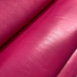 May include: Close-up of a vibrant pink leather fabric with a smooth, slightly textured surface.